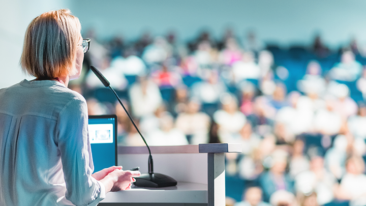 Woman speaking to crowd at a large conference