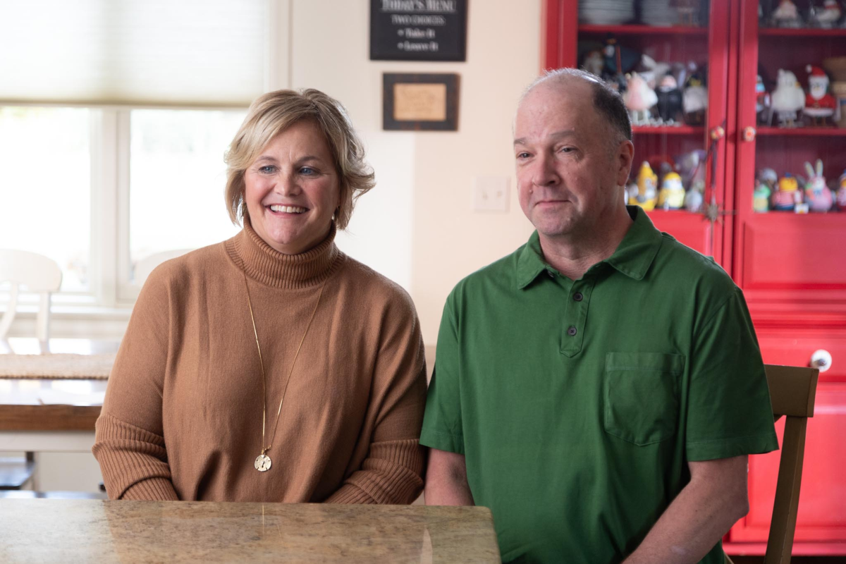 Krueger family parents sitting in dining room with red shelf in the background