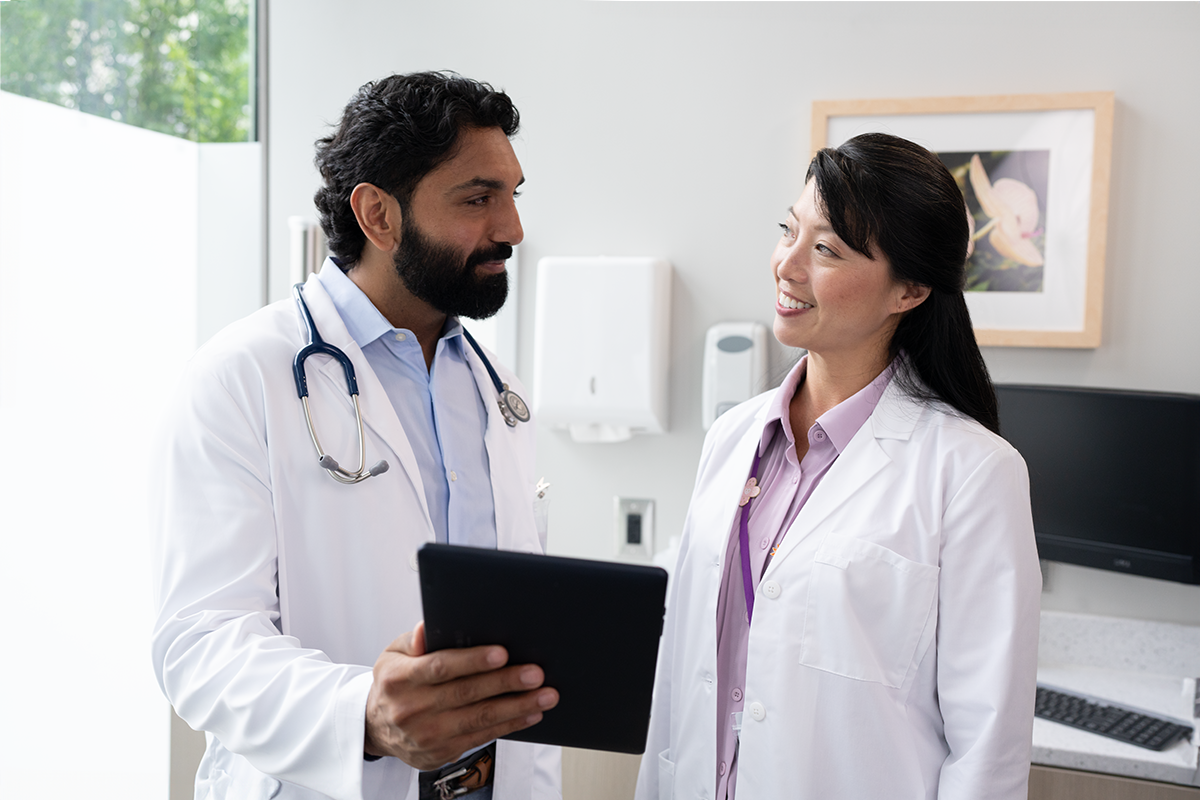 Two HCPs in white lab coats discussing results while one is holding a clip board