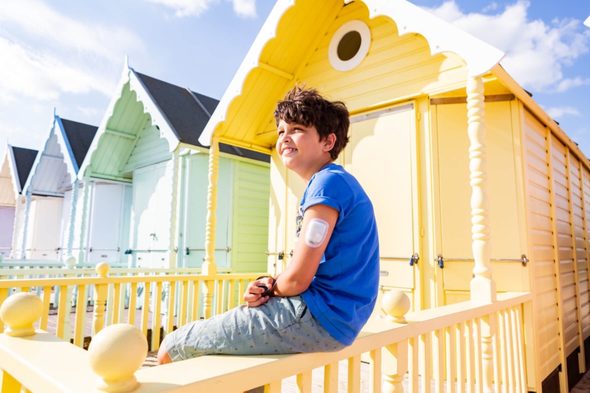 Omnipod Podder boy sitting at huts on the beach on a sunny day