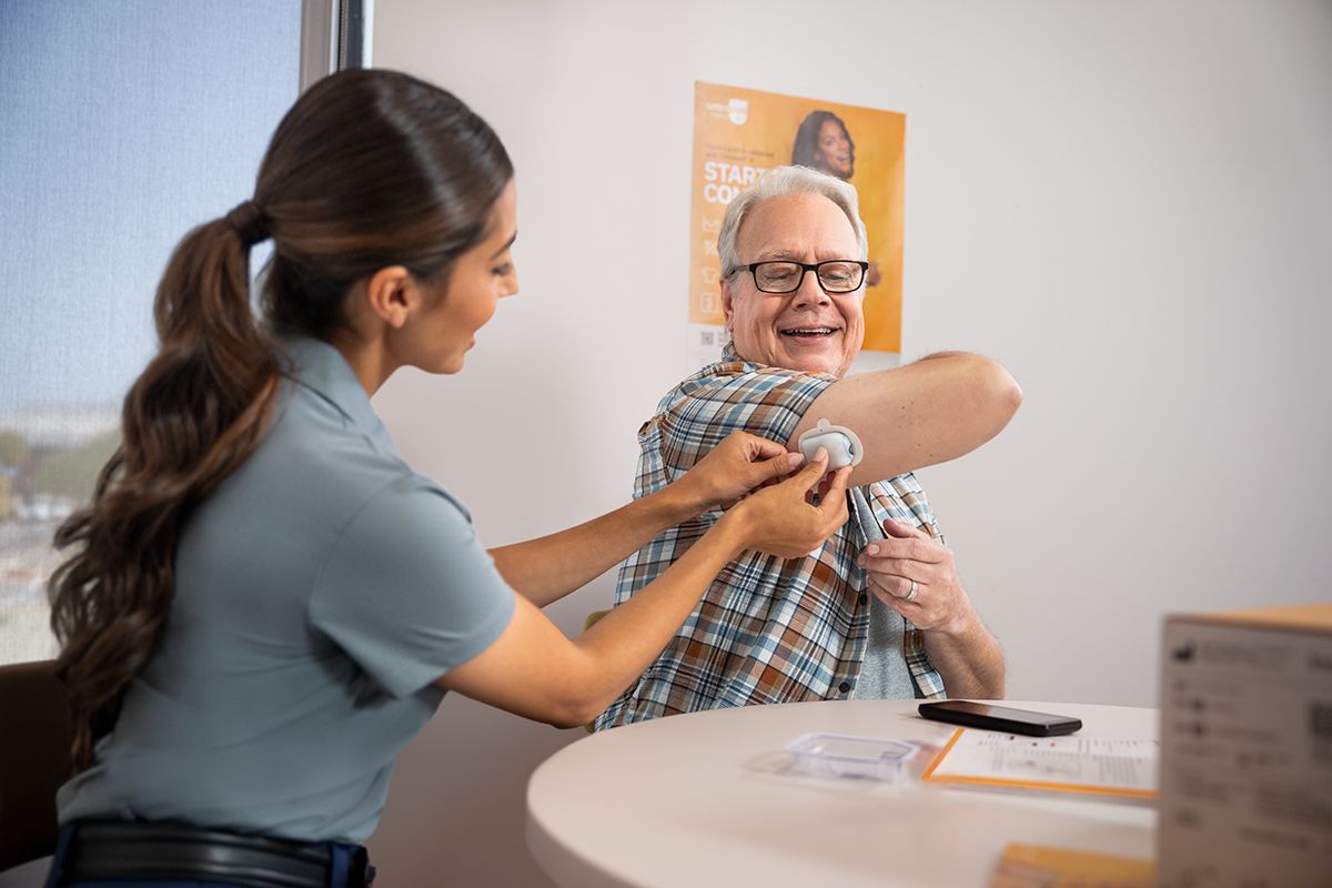 Omnipod CSM helping patient with applying a Pod on his right arm
