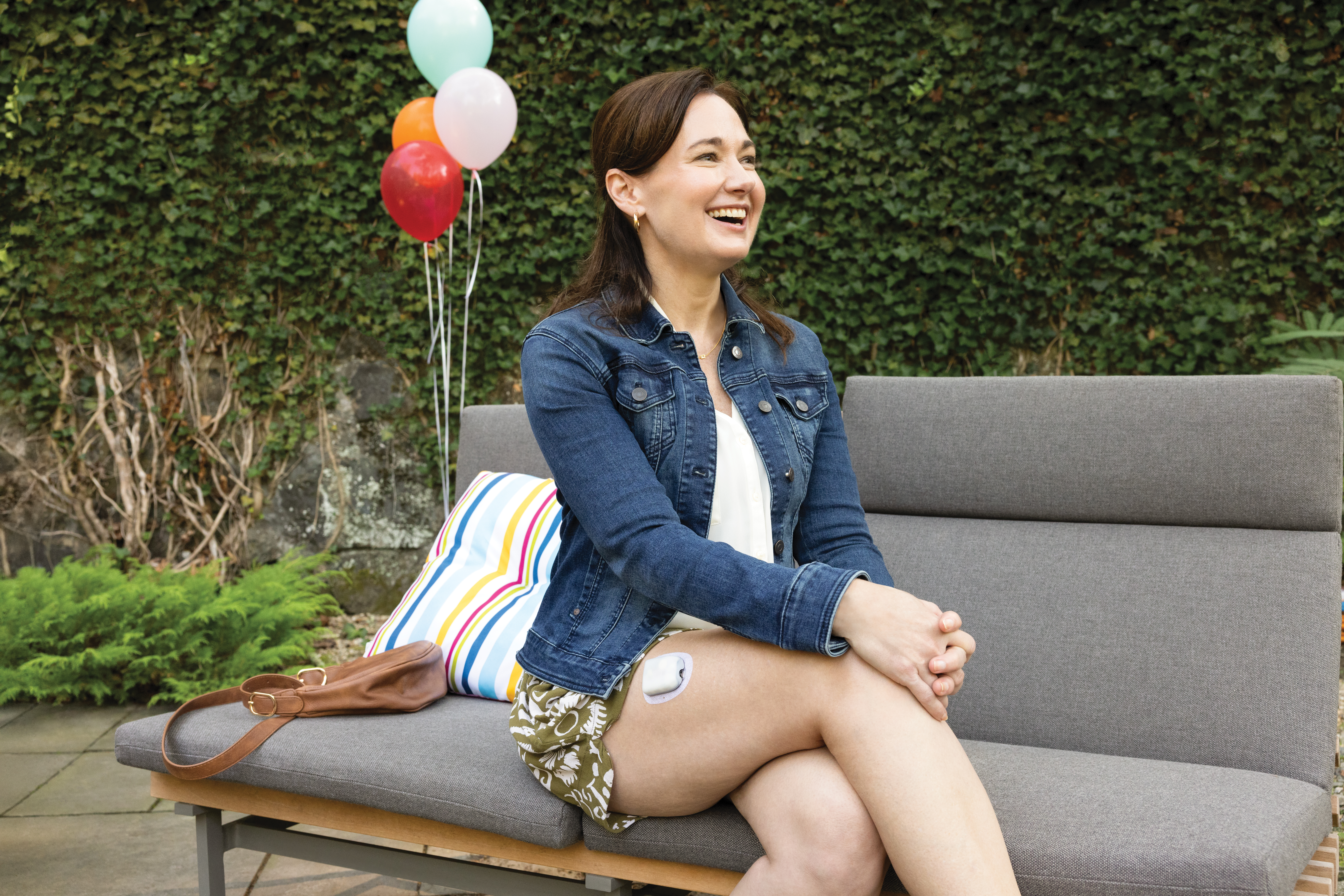 Lady sit in a sofa outside wearing an insulin pump