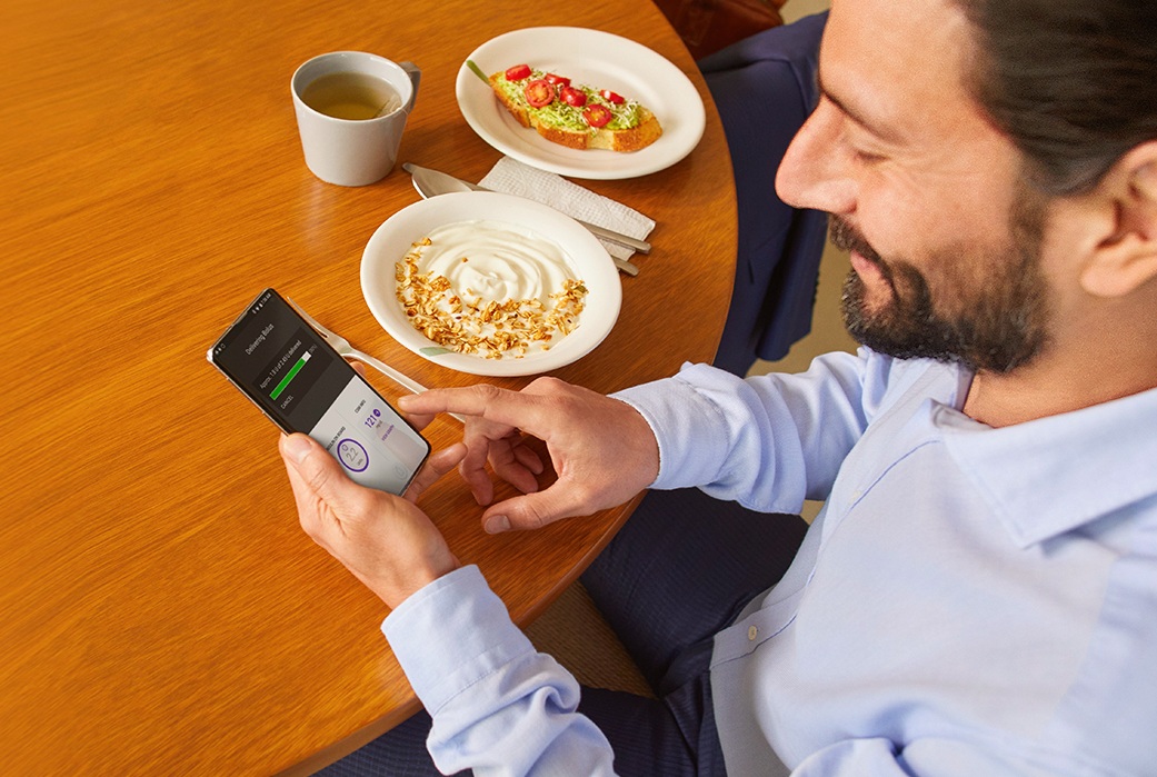 Business man breakfast and checking insulin pump