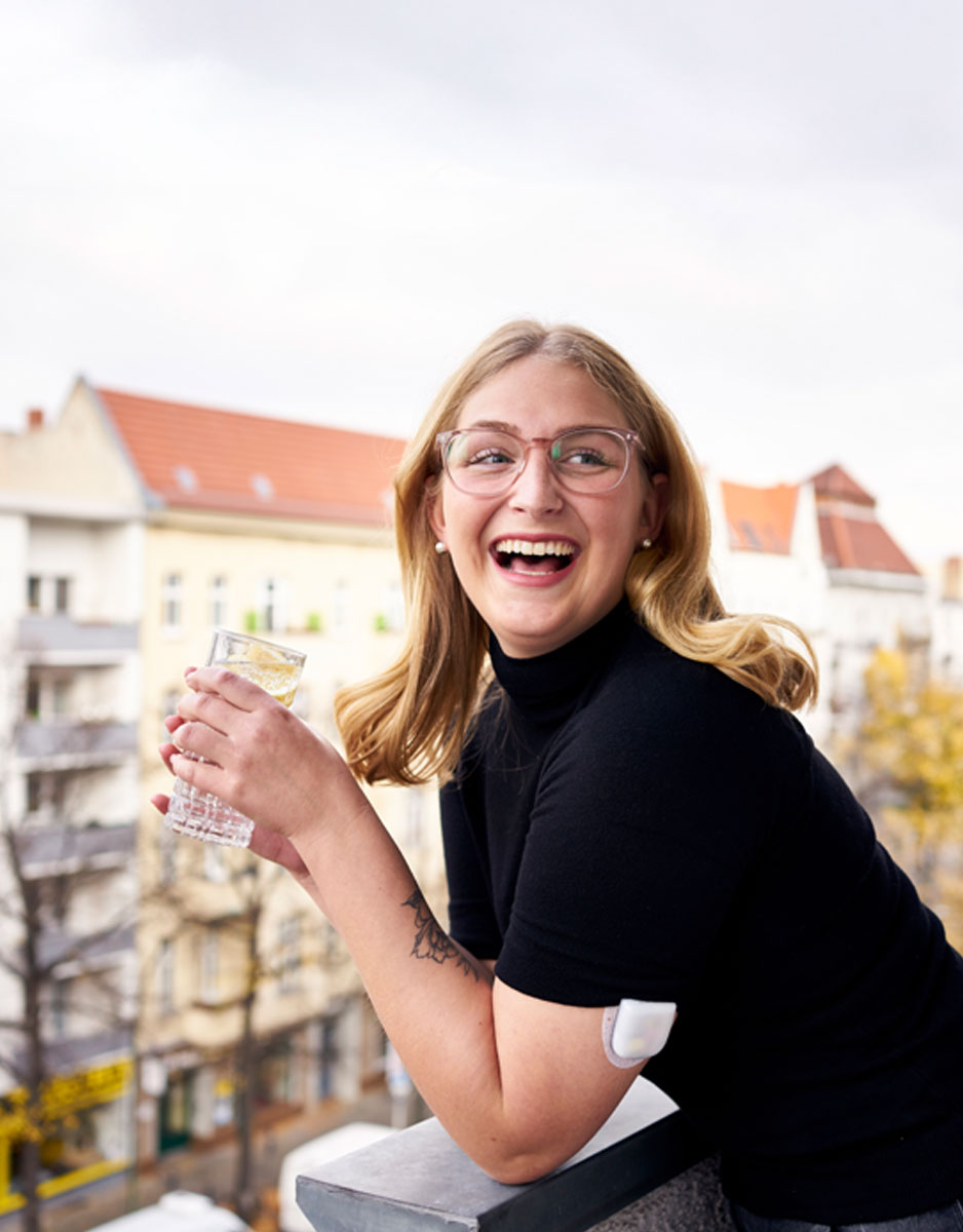 podder Jule on balcony with glass in hand smiling
