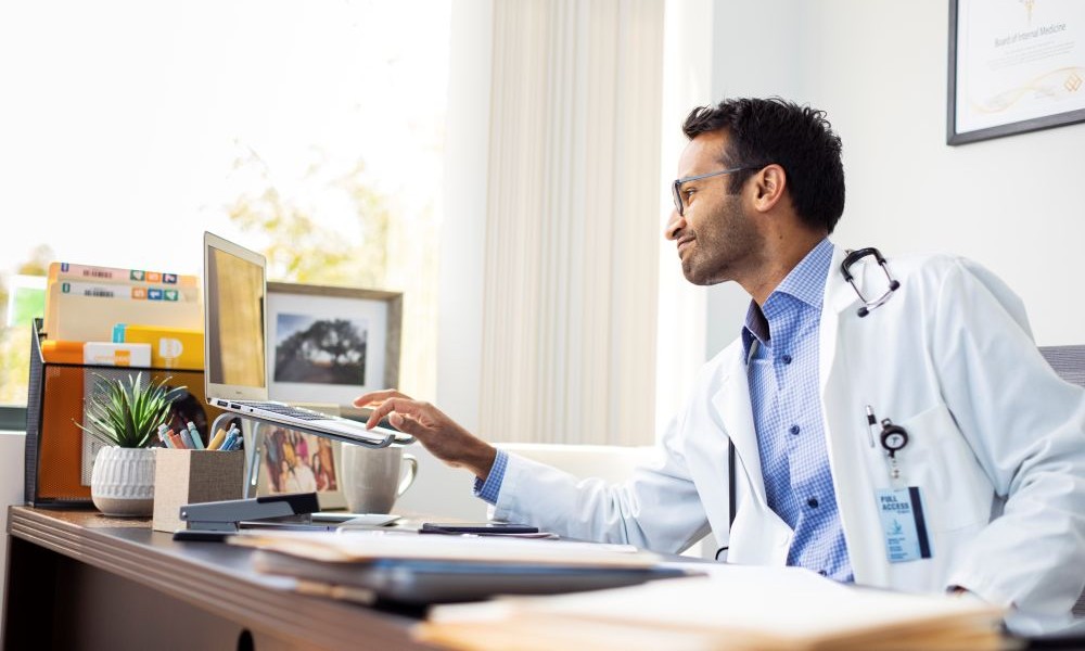 Healthcare professional sitting at his desk on his laptop