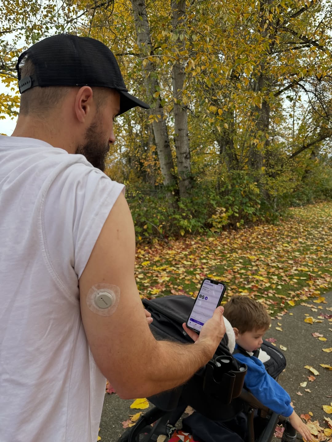 man holding Omnipod controller while pushing his son in a stroller 