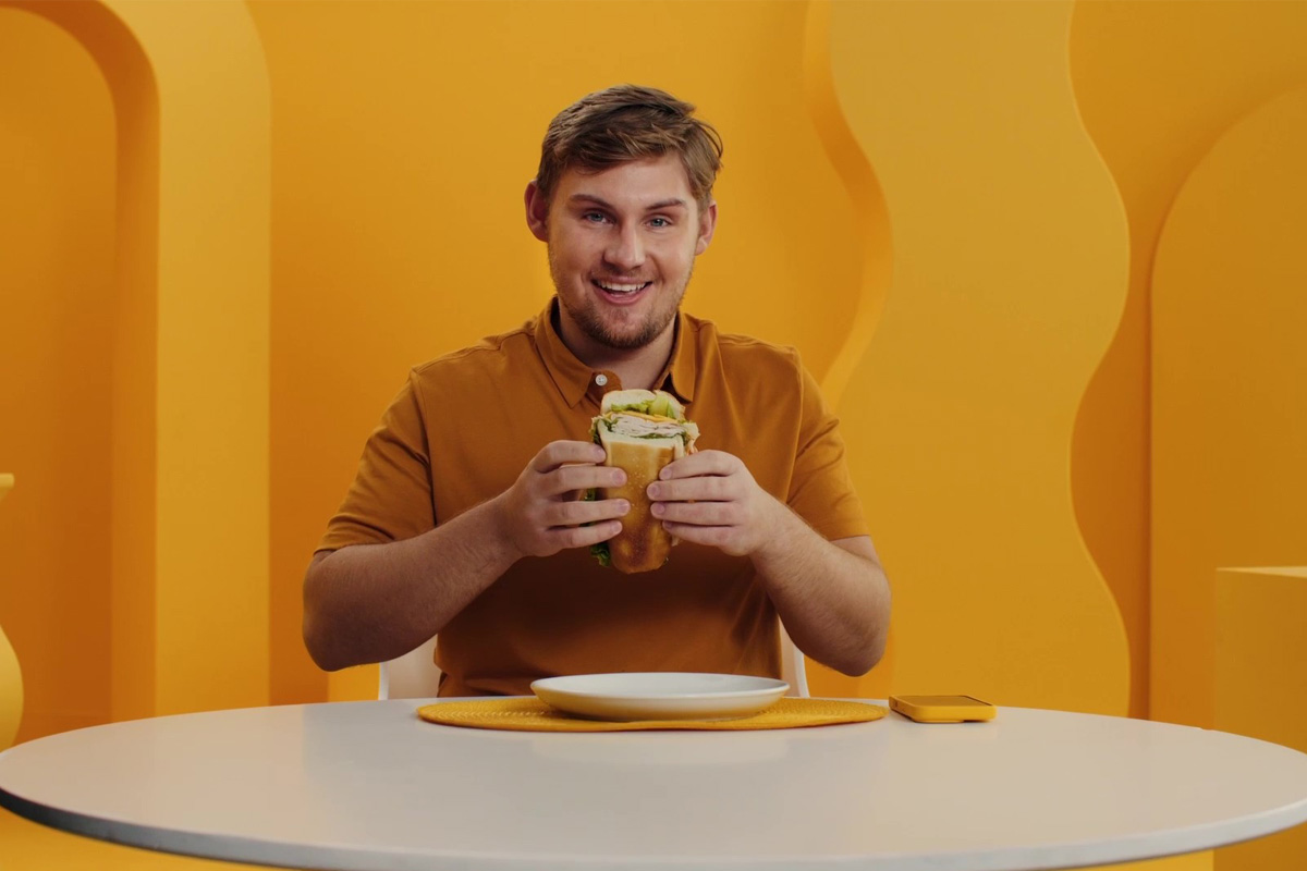 Man holding a submarine sandwich and smiling