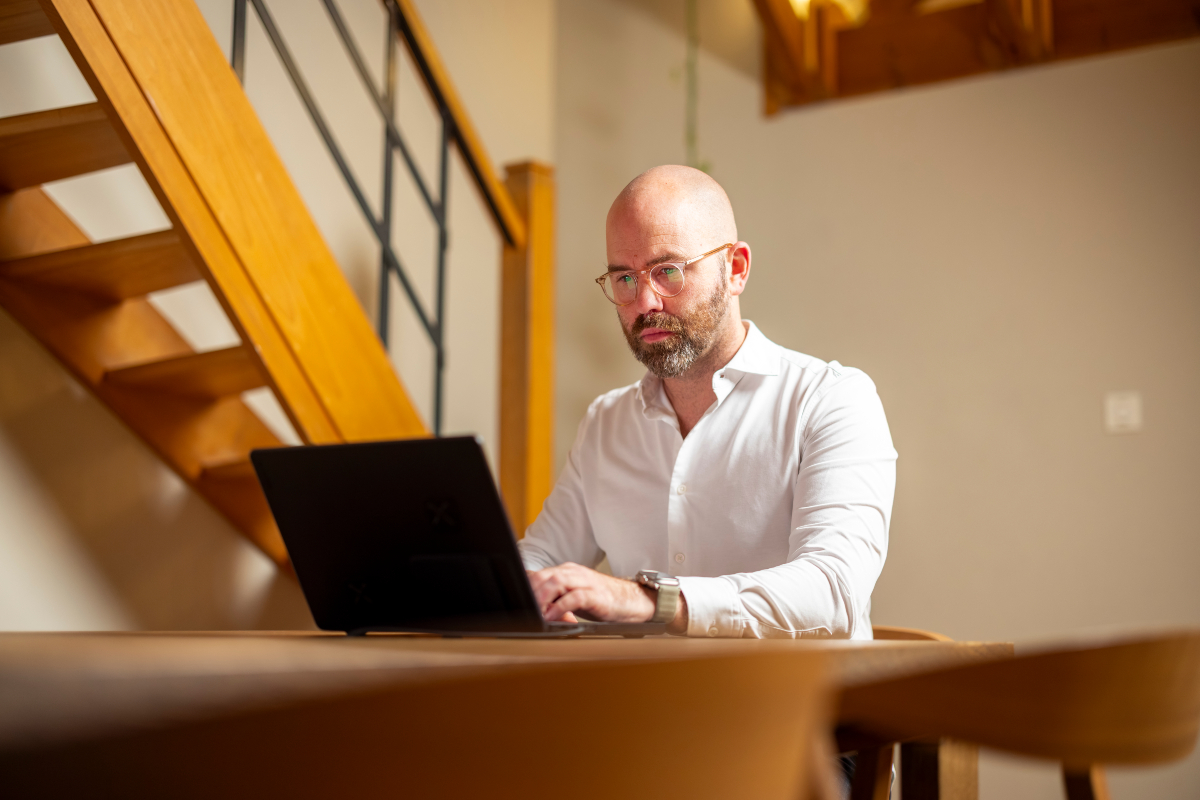 Man working on laptop near stairs