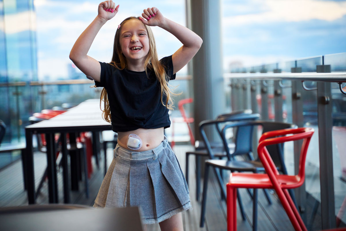 girl with arms raised excited while wearing a pod on her abdomen