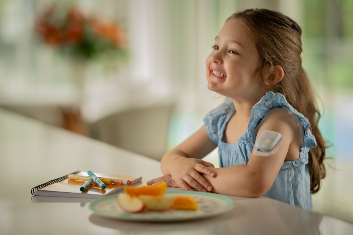 Podder, sitting at the table with a book and crayons, and a plate of eaten oranges