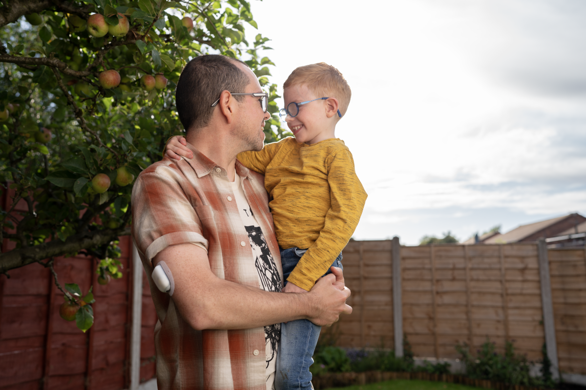 Podder, holding his son in the garden, wearing an Omnipod