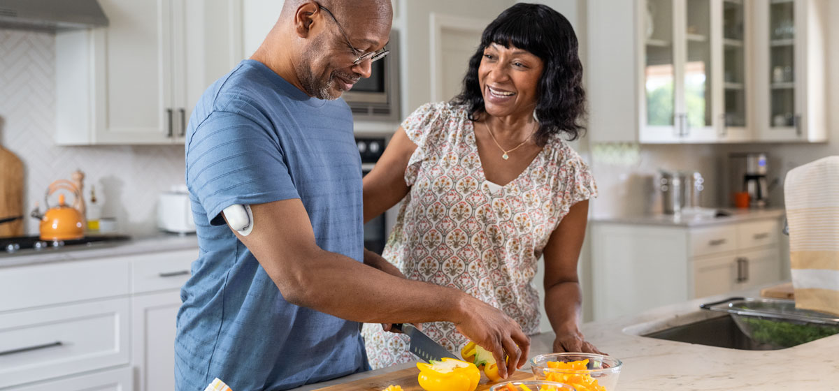 a couple cutting fruit in the kitchen
