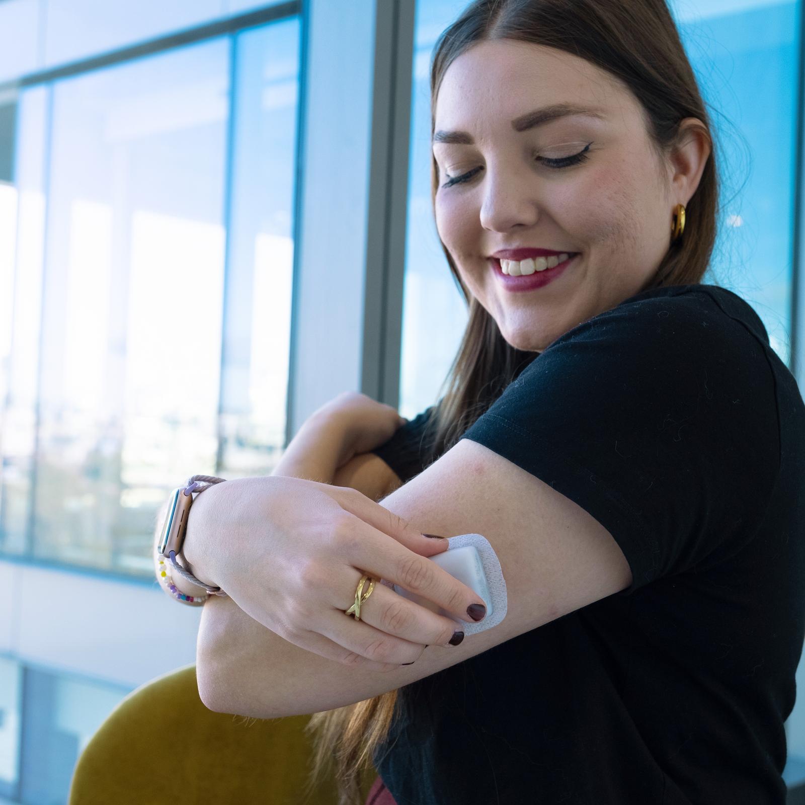 woman placing pod on her upper arm