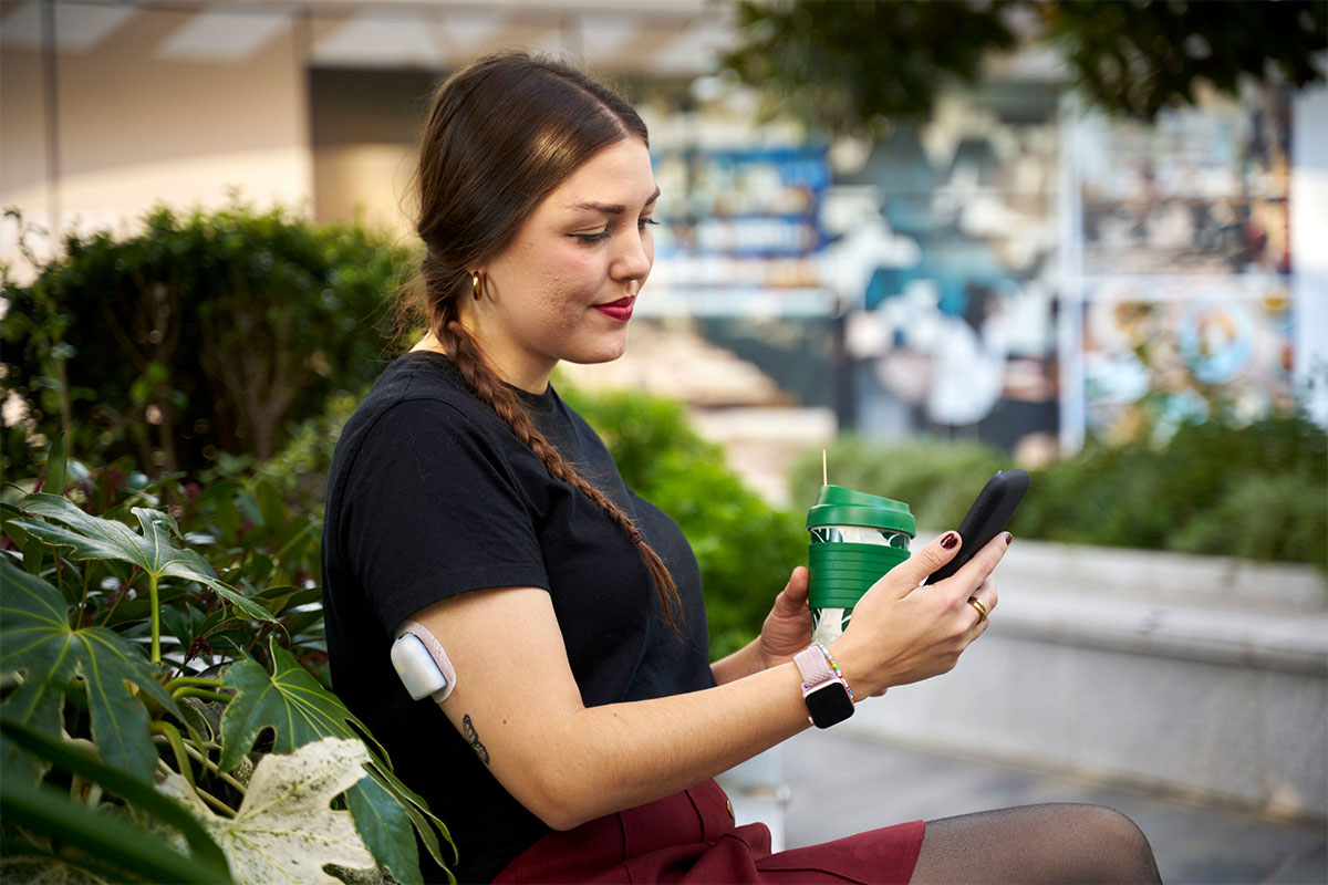 woman holding her phone and a drink