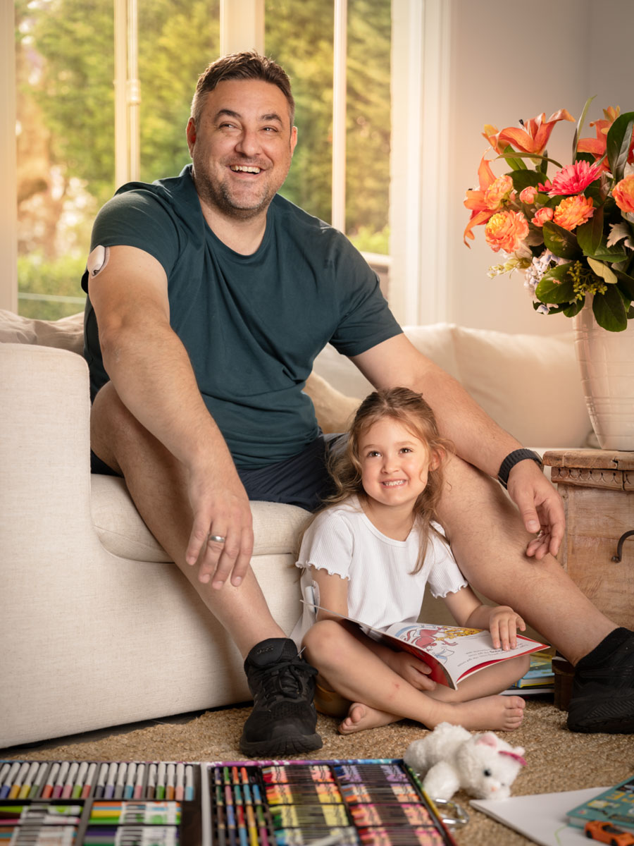 father and daughter sitting in living room with toys on the floor