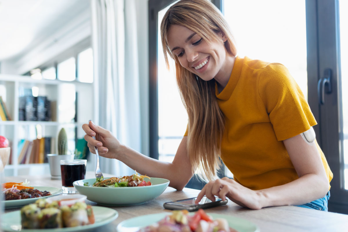 woman at a restaurant smiling while looking at a phone