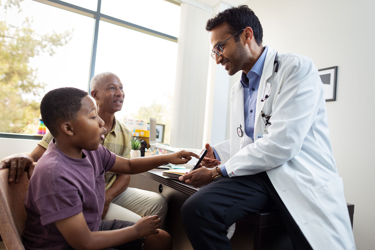 doctor showing a child something on a screen with a parent looking on