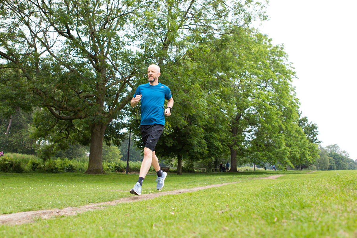 Man with diabetes wearing a glucose sensor on his upper arm while jogging outdoors