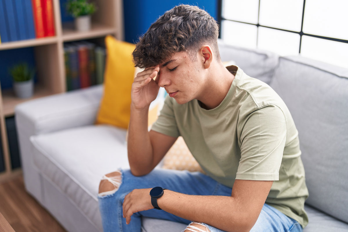 Person sitting on a couch resting their head in one hand
