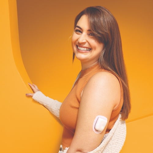 Omnipod Podder, Meg, at a photoshoot with an orange colored backdrop.