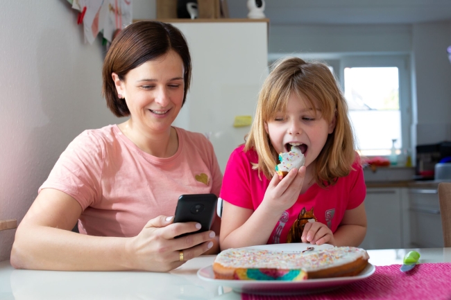 Girl sitting next to her Mum eating cake