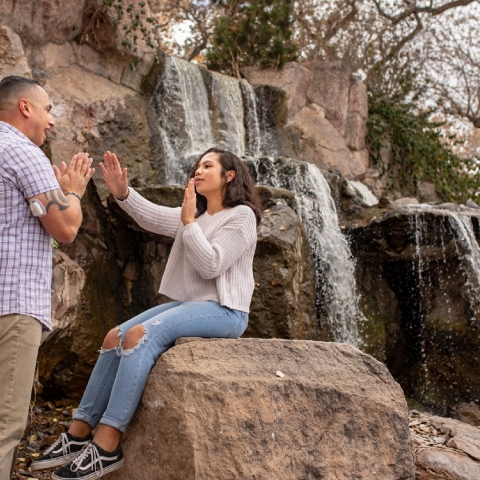 Father and daughter playing Patty Cake, sitting by a waterfall