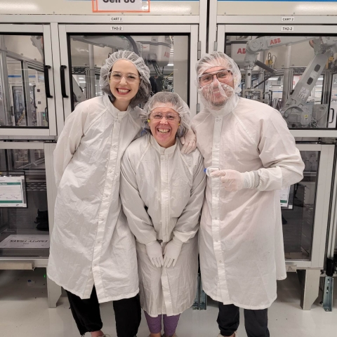 Three people in lab coats smiling to camera