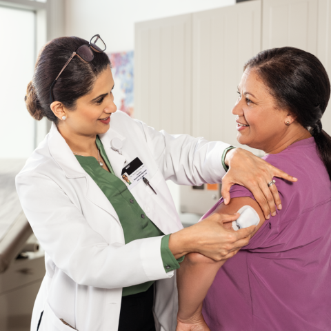 HCP placing a Pod on a patient's left arm while their in a doctor's office