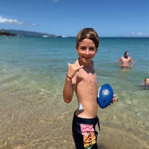 Tadgh holding a football at the beach