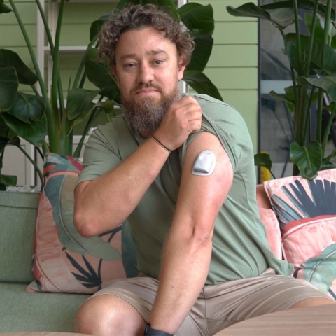 man holds the sleeve up to show the Pod off on his arm